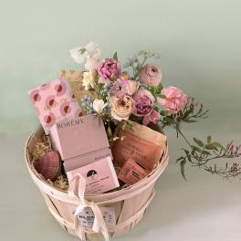 Pink flower bouquet in a wooden basket with bath and perfume gifts