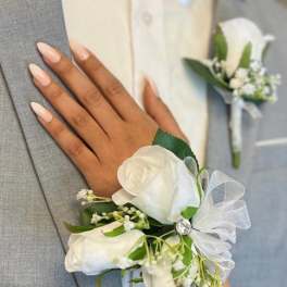 White rose corsage on a gray suit jacket with a matching boutonniere