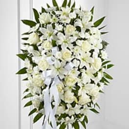 White funeral spray with lilies and roses on a standing easel