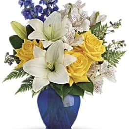 Yellow roses and white lilies in a blue vase