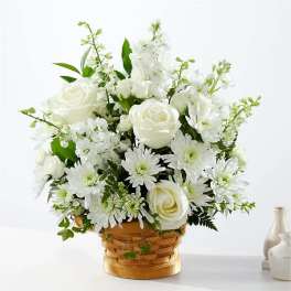 White roses and daisies arranged in a woven basket