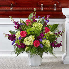 Pink roses and purple flowers in a white vase arrangement