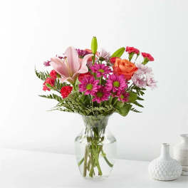 Mixed bouquet of pink and orange flowers in a clear glass vase