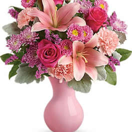 Pink floral bouquet in a pink vase with lilies and roses