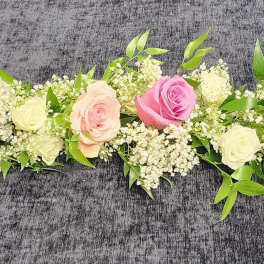 Long floral garland with pink and cream roses on a dark surface