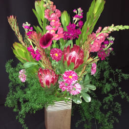 Tall floral arrangement with pink and magenta blooms in a rectangular vase