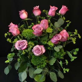 Pink roses arranged in a glass vase with greenery