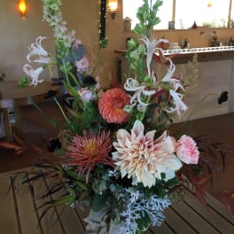 Tall mixed floral arrangement in a glass vase with pink, white, and coral blooms