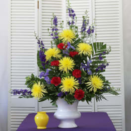 Tall floral arrangement in a white vase with yellow, red, and purple flowers