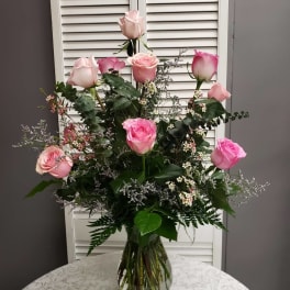 Tall arrangement of light and bright pink roses with delicate white fillers in a clear glass vase