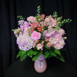 Pink and lavender floral arrangement in a pink vase with a bird tag