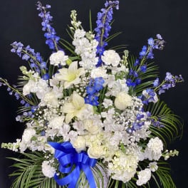 White and blue floral arrangement in a basket with a blue ribbon