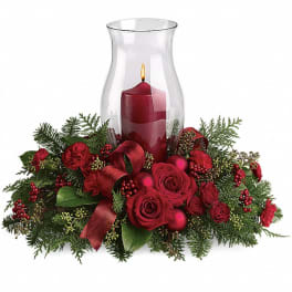 Red candle in a glass hurricane surrounded by roses and evergreen
