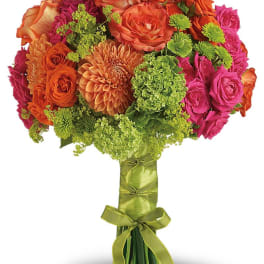 Bouquet of orange and pink roses with green accents and a ribbon-wrapped handle