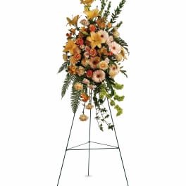 Tall floral standing spray with yellow lilies, peach roses, and gerbera daisies