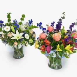 Two mixed flower arrangements in glass vases, one white and blue and one pink, yellow, and purple.
