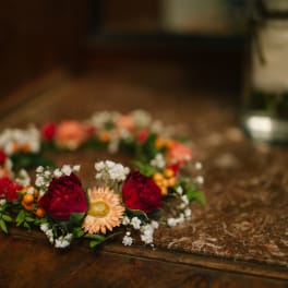 Floral crown with red roses and peach daisies on a table