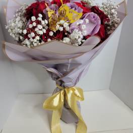 Bouquet of red and lavender roses with white baby's breath and a yellow butterfly topper