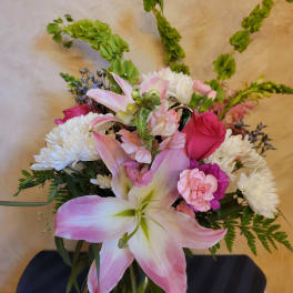 Pink lilies and roses with white chrysanthemums in a glass vase