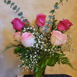 Pink roses in a glass vase with baby's breath and eucalyptus
