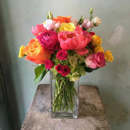 Colorful bouquet of roses and ranunculus in a clear glass vase