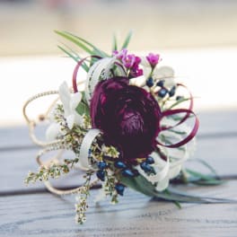 Small floral corsage with a dark purple bloom and white accents