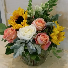 Mixed bouquet with roses, sunflowers, and snapdragons in a glass vase