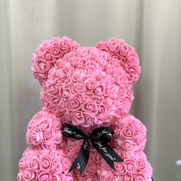 Pink teddy bear made of roses with a black ribbon