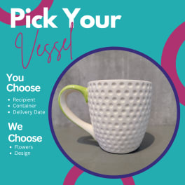 White textured mug with a green handle on a gray surface
