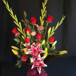 Tall bouquet of red roses and pink lilies in a glass vase