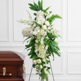 White funeral spray with roses and chrysanthemums on an easel beside a casket