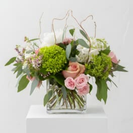 Pink roses and green blooms arranged in a clear glass vase