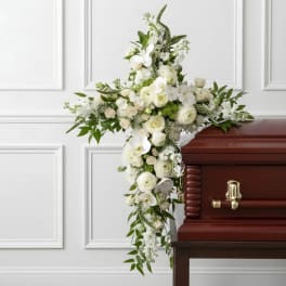 White floral cross arrangement displayed on a casket