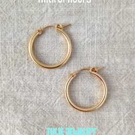 Pair of gold hoop earrings on a textured fabric background