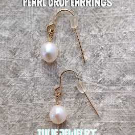 Pair of pearl drop earrings on a textured fabric background
