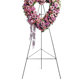 Heart-shaped pink rose wreath on a standing easel with ribbon