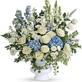 White and blue floral arrangement in a white pedestal vase
