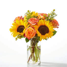 Bouquet of sunflowers and orange roses in a clear glass vase