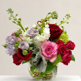 Mixed roses and white blooms arranged in a clear glass vase