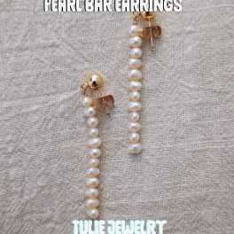 Pair of pearl drop earrings on a textured fabric background