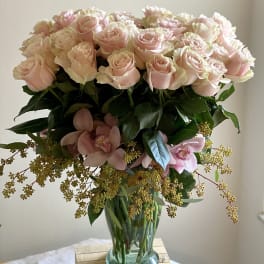 Bouquet of pale pink roses and orchids in a glass vase