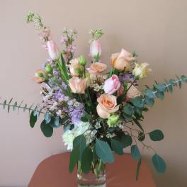 Mixed pastel bouquet in a clear glass vase with roses and tulips