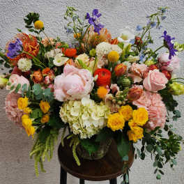 Large mixed bouquet in a vase with pink, yellow, orange, purple, and white flowers