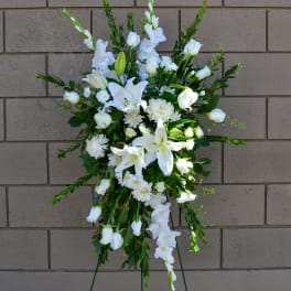 White floral standing spray with lilies and daisies on an easel