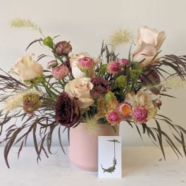 Mixed bouquet of blush and burgundy flowers in a pink vase