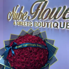 Large bouquet of red roses wrapped in dark paper with a Valentine ribbon