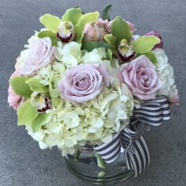 Bouquet of pale pink roses, hydrangeas, and green orchids in a glass vase
