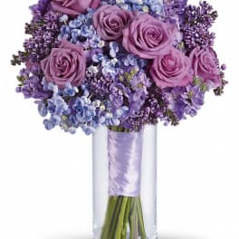 Purple roses and lilac flowers in a clear glass vase
