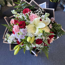 Bouquet of red roses, white lilies, and pink carnations wrapped in black paper