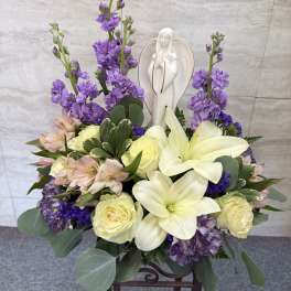 Purple and cream floral arrangement with a white angel figurine